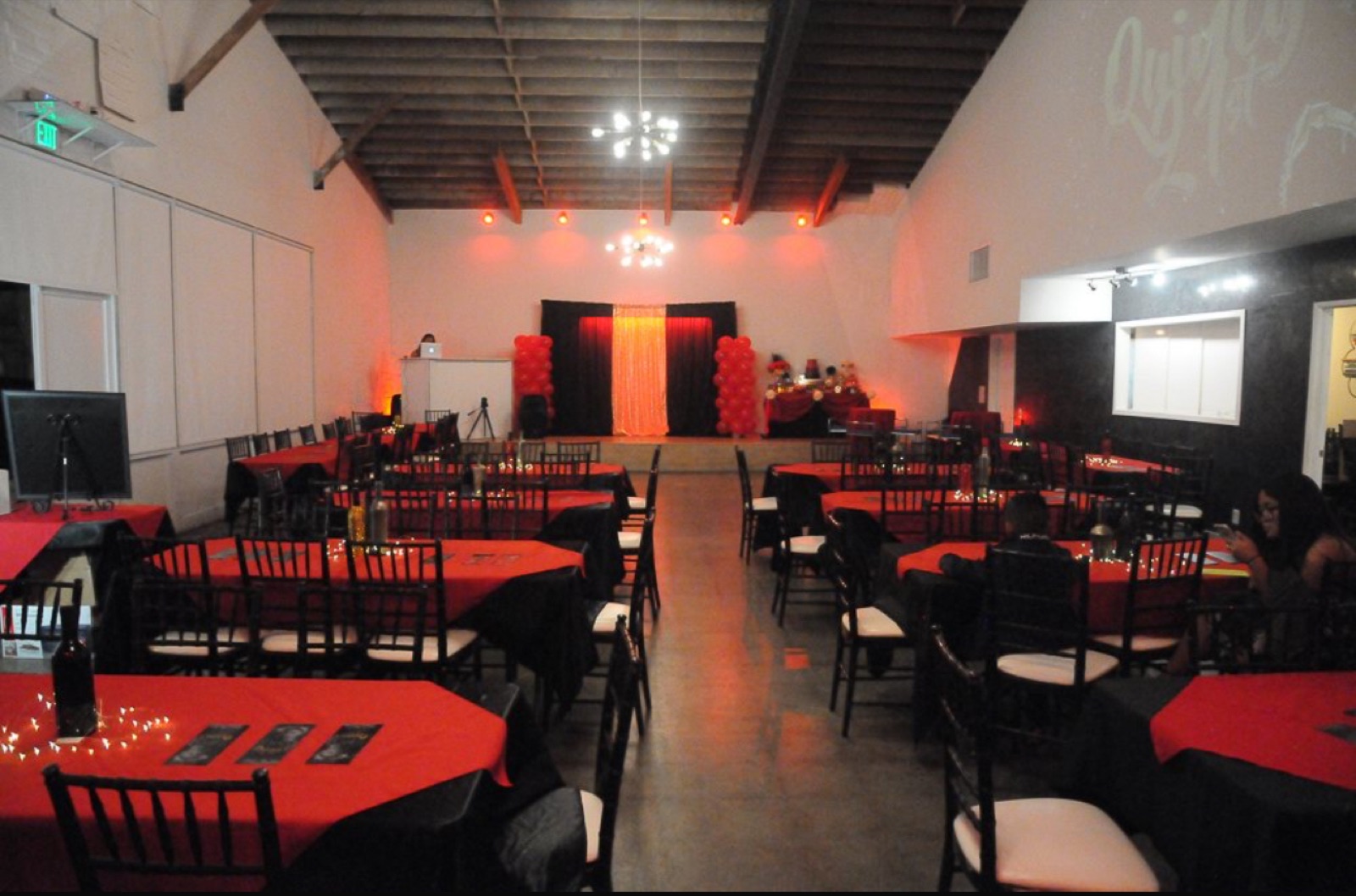 The Shelby warm red-uplit celebration with vaulted wood-beam ceiling visible